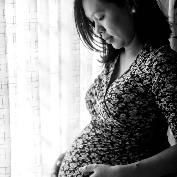 Black and white photo of a pregnant lady looking down at her bump