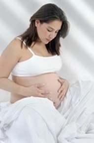 Photo of a pregnant lady sitting crossed-legged holding her bump